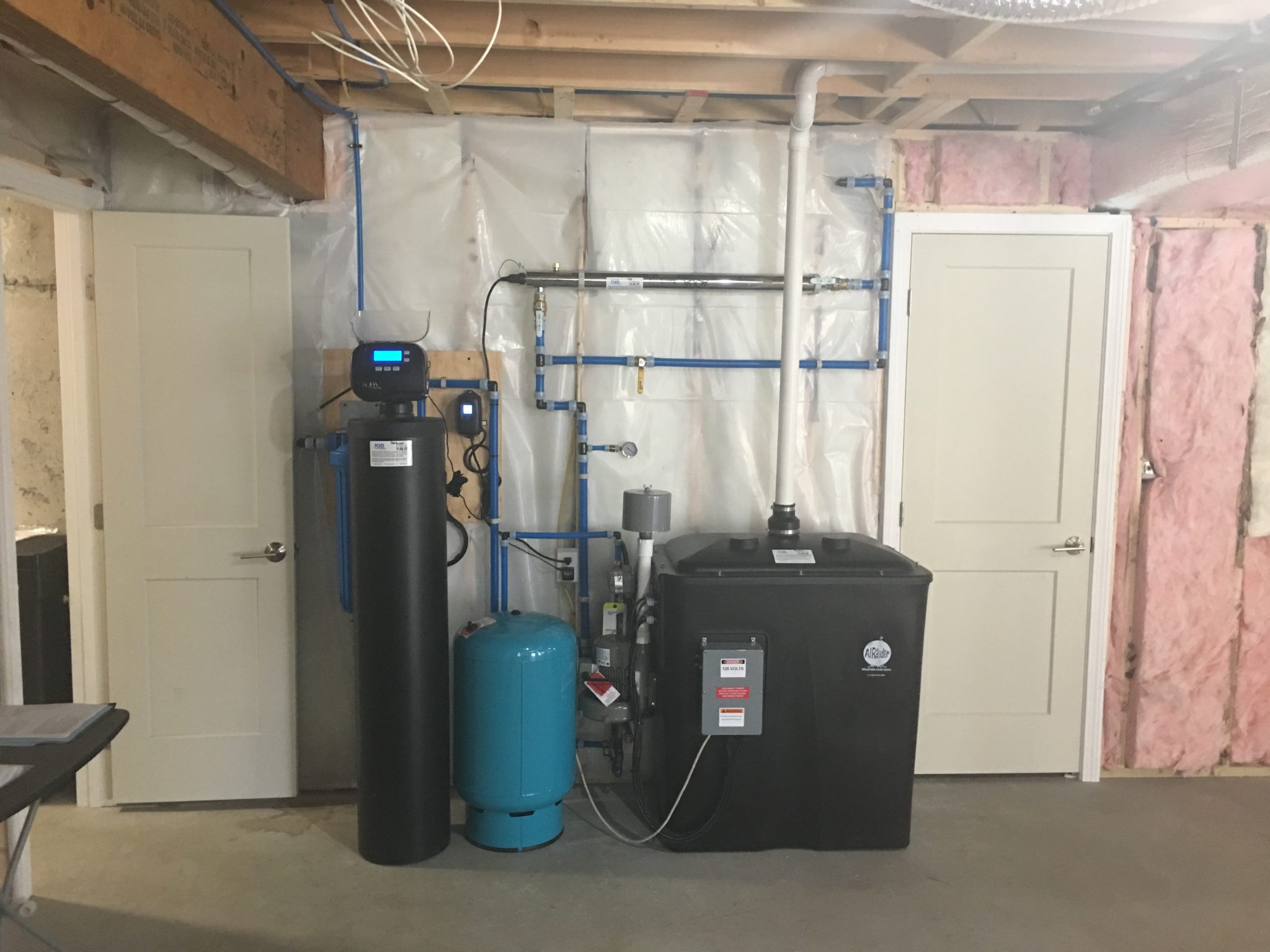 From right, Radon in water removal system with pressure tank (blue) and 1 1/2 cubic feet high efficiency Water Softener. 20" graded density sediment filter behind softener.