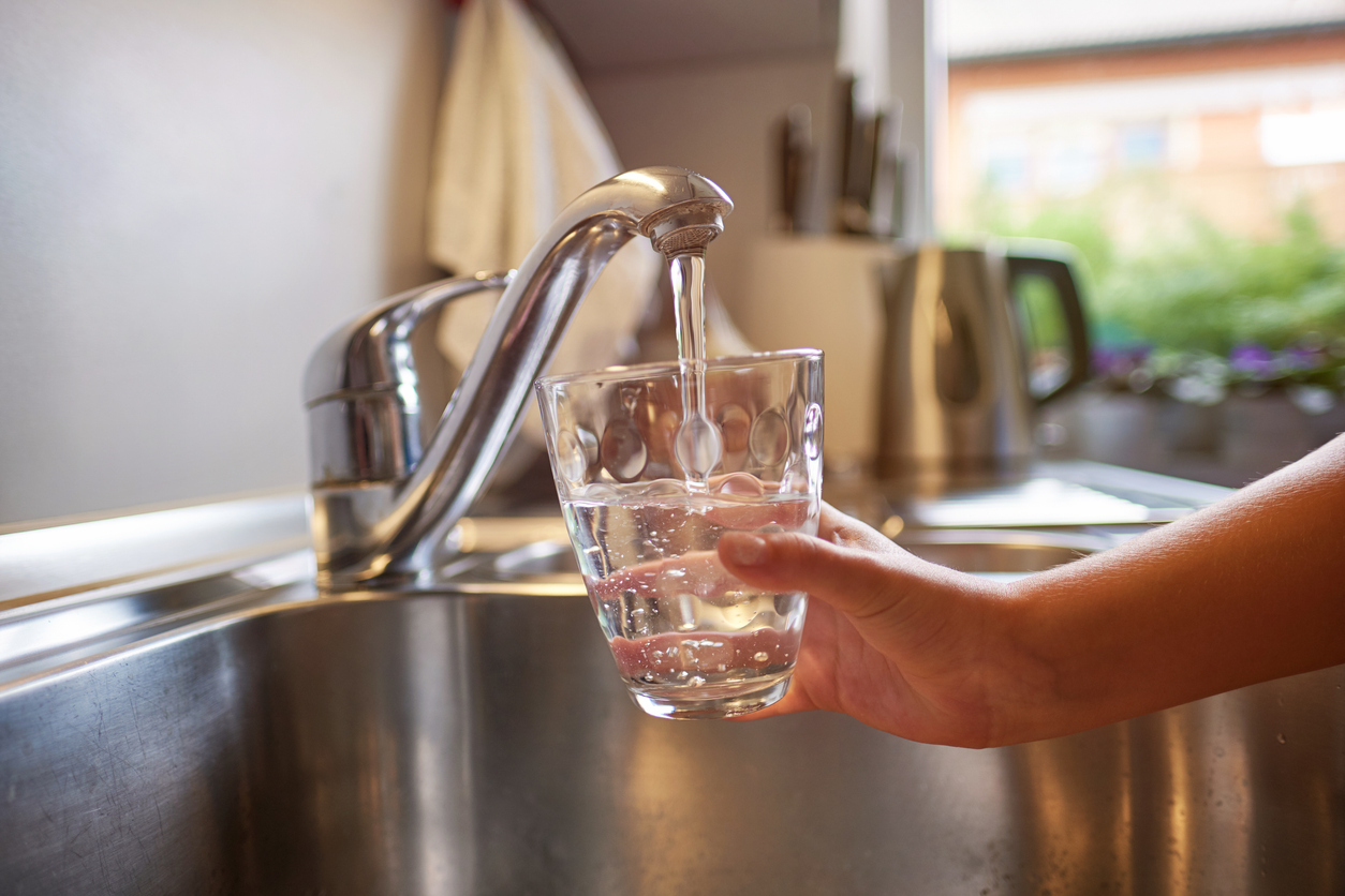  Person filling a drinking glass with water from the tap