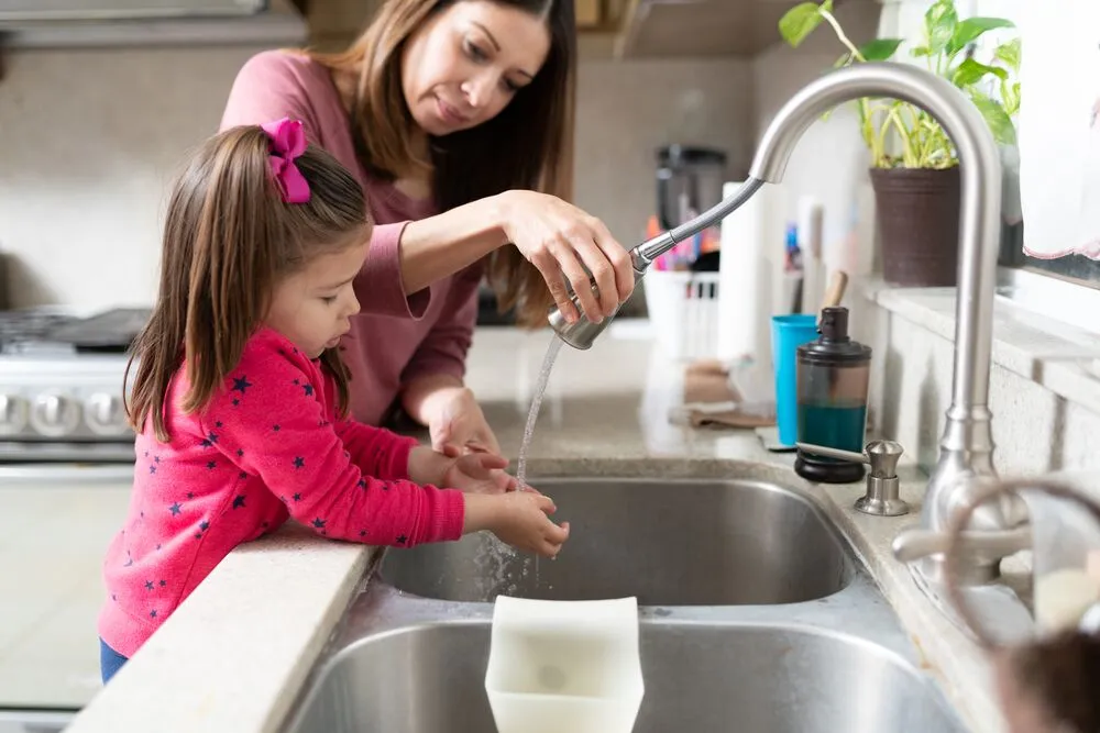 Mother and daughter washing hands in sink