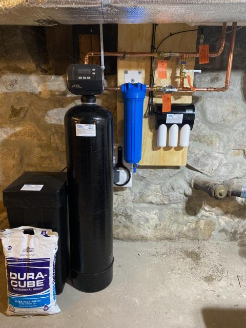 A water treatment system in a basement beside a bag of softener salt