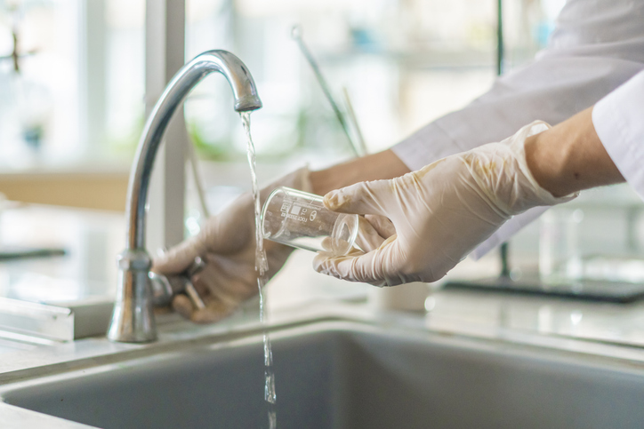 Someone holding a test tube under water facet