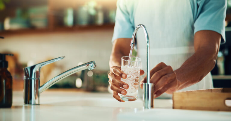 Person, tap and hands with glass of water in kitchen for fresh drink